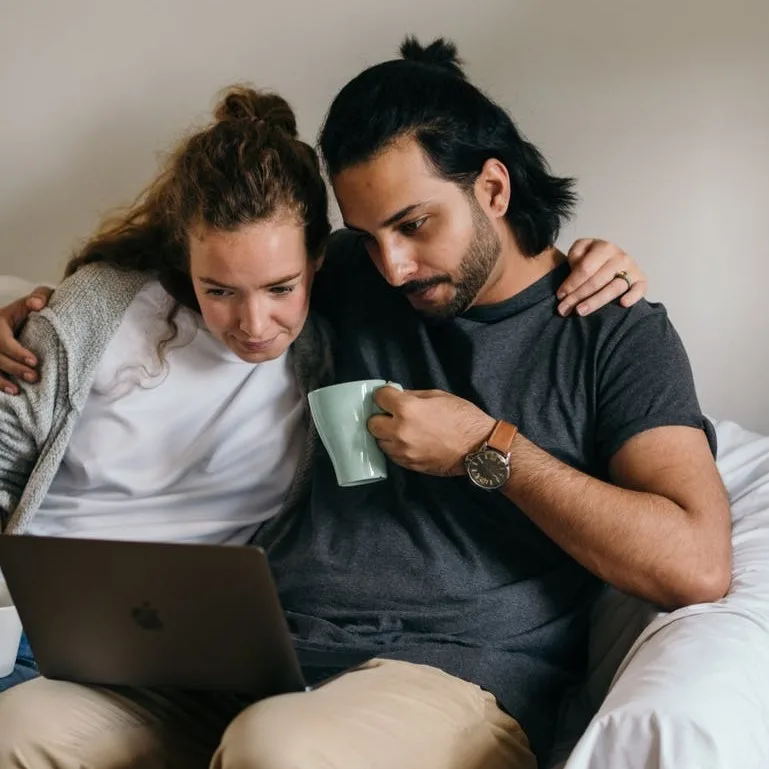 couple closely sitting together on a sofa looking at a laptop